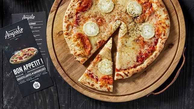 Uma pizza de queijo de cabra cortada numa tábua de madeira, com a carta ao lado