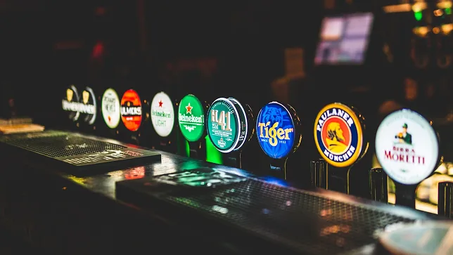 Uma fila de torneiras de cerveja iluminadas no balcão do bar