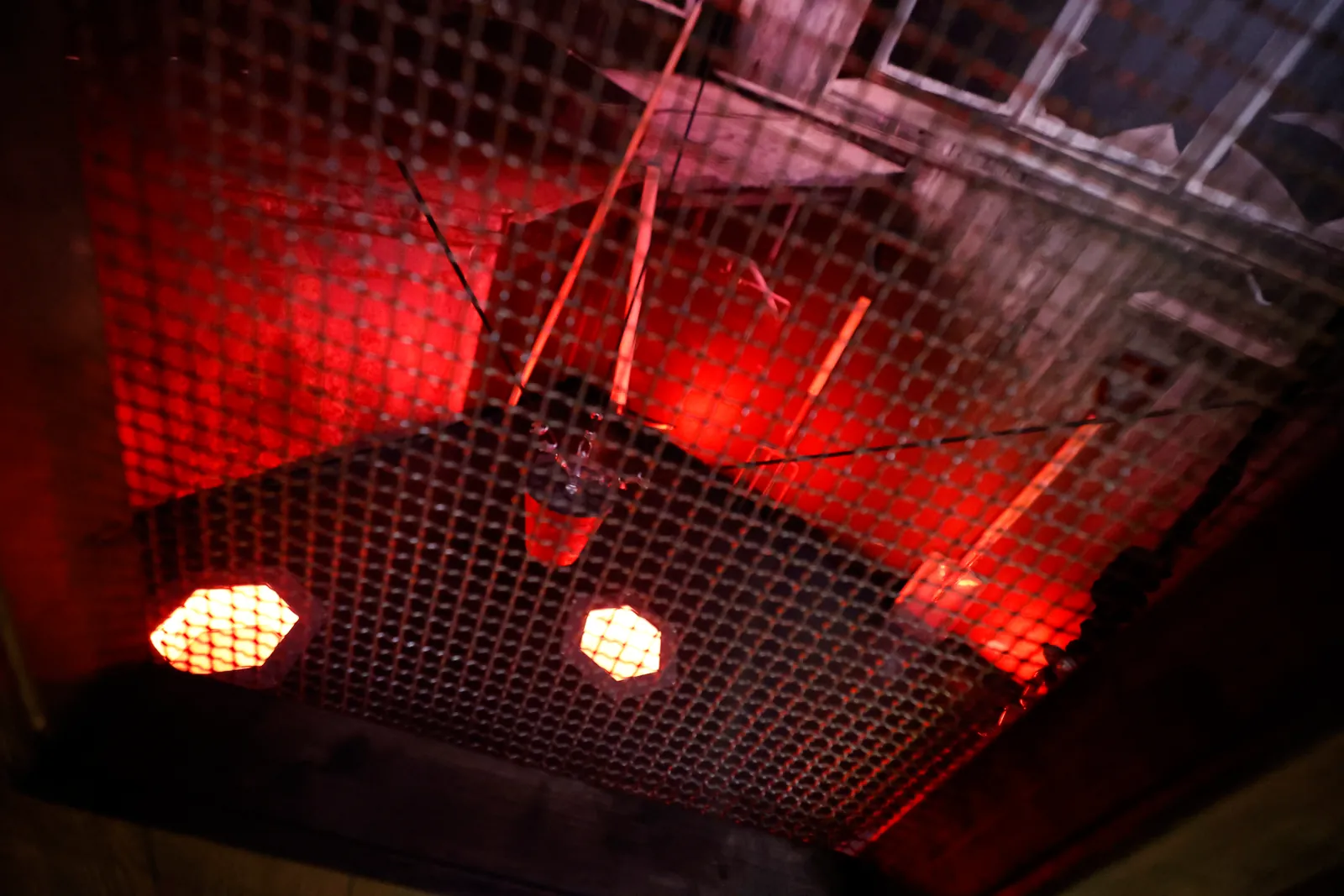 Uma cela iluminada a vermelho, com uma rede esticada no teto