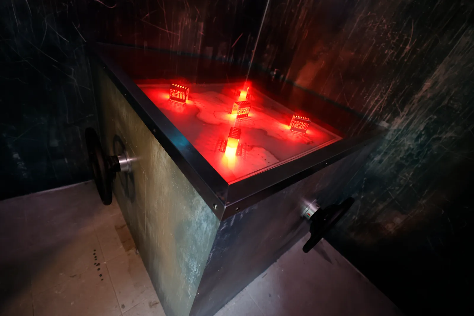 Uma cela escura com um recipiente vermelho iluminado e alvos para acertar